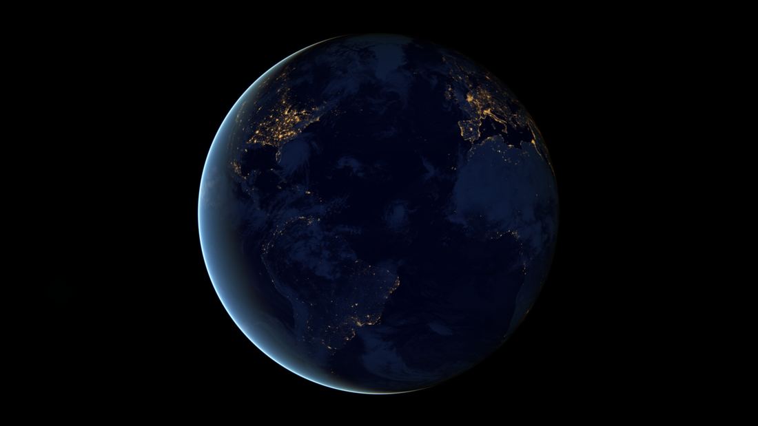 A map of Earth at night with glowing city lights tracing coastlines, rivers and highways