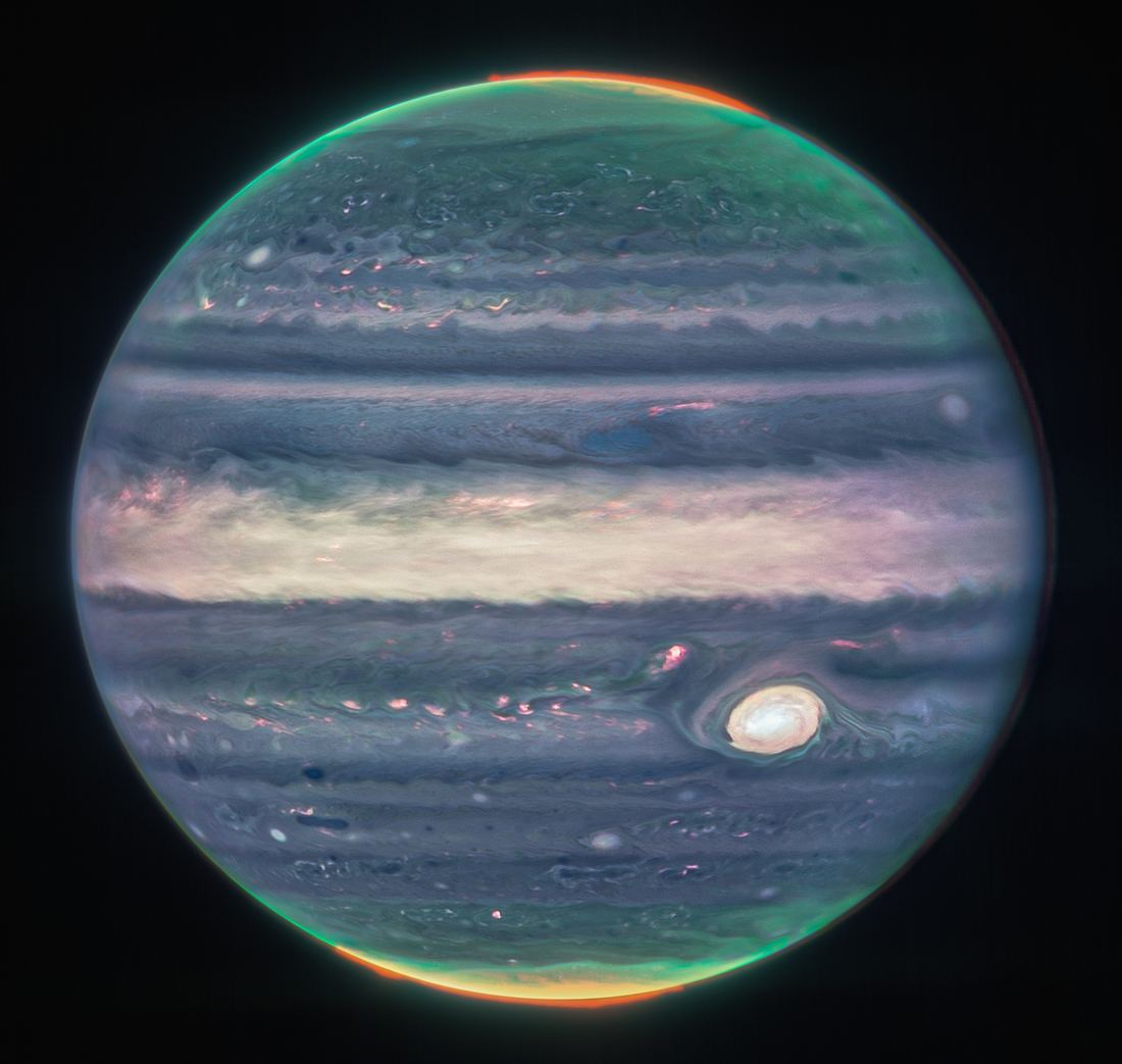 An infrared Webb image of Jupiter in blue, white and orange tones with glowing auroras at the poles